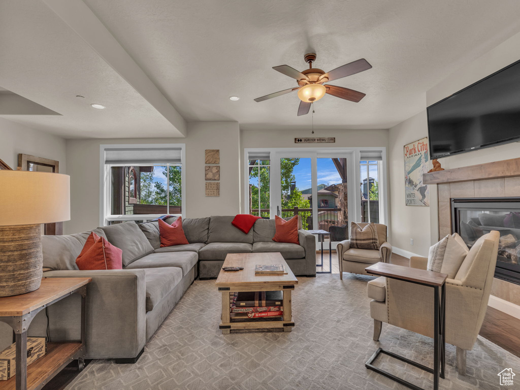 Living room with plenty of natural light, baseboards, ceiling fan, a tiled fireplace, and recessed lighting