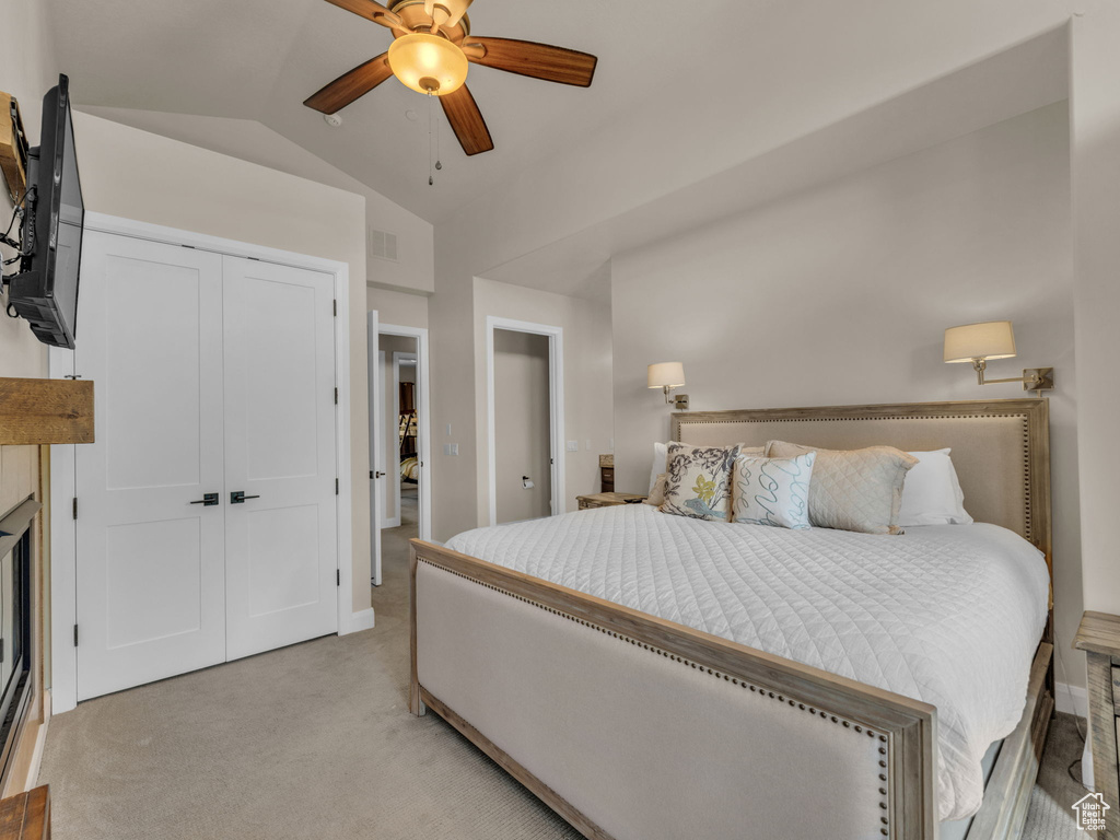Bedroom with vaulted ceiling, light colored carpet, baseboards, ceiling fan, and a closet