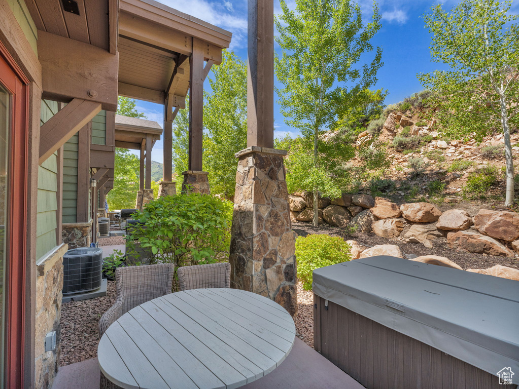 View of patio with a hot tub, central AC, and outdoor dining area