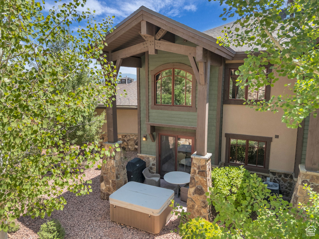 Back of house featuring stone siding and a patio