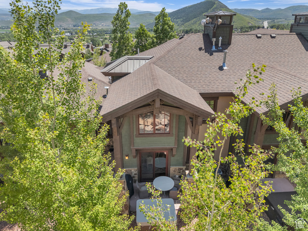 View of front of home featuring roof with shingles, stone siding, and a mountain view