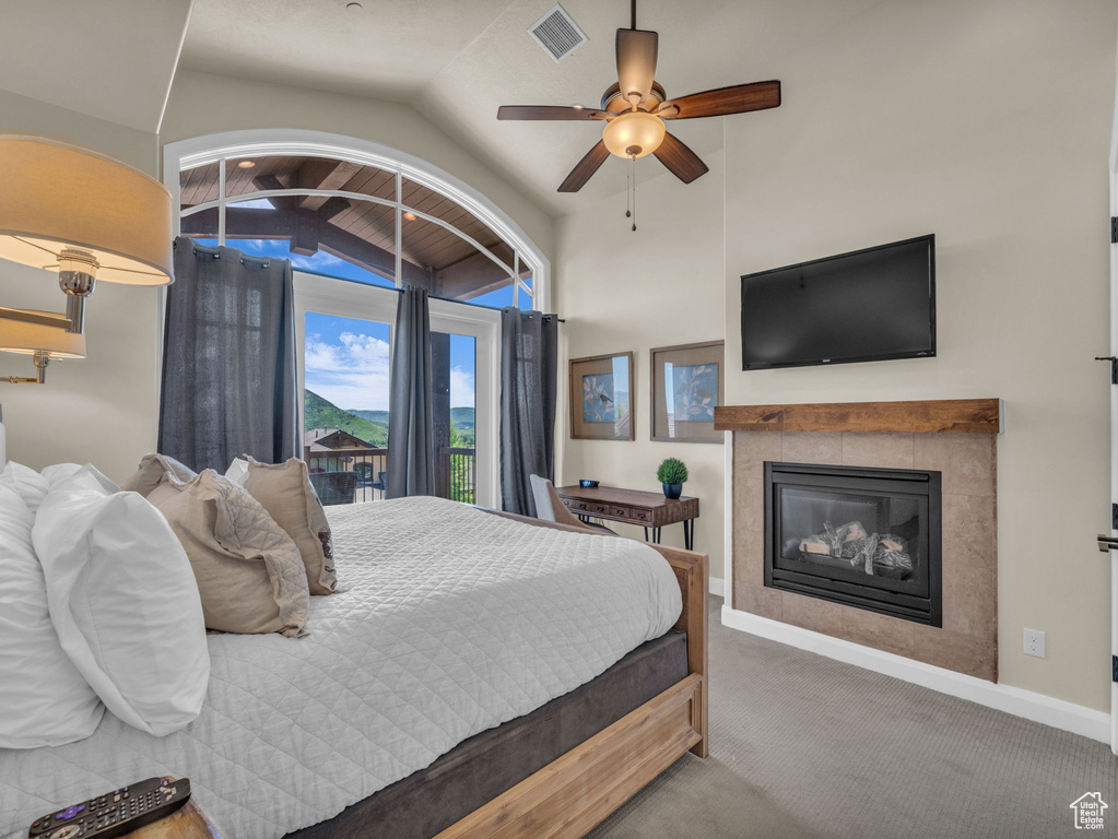 Carpeted bedroom featuring lofted ceiling, a tile fireplace, baseboards, and ceiling fan