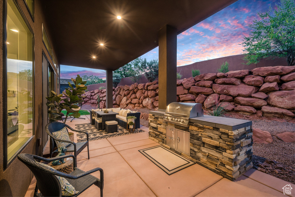 Patio terrace at dusk featuring an outdoor hangout area, grilling area, and an outdoor kitchen