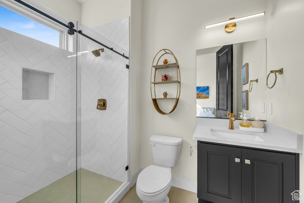 Bathroom featuring vanity, a shower with door, and toilet