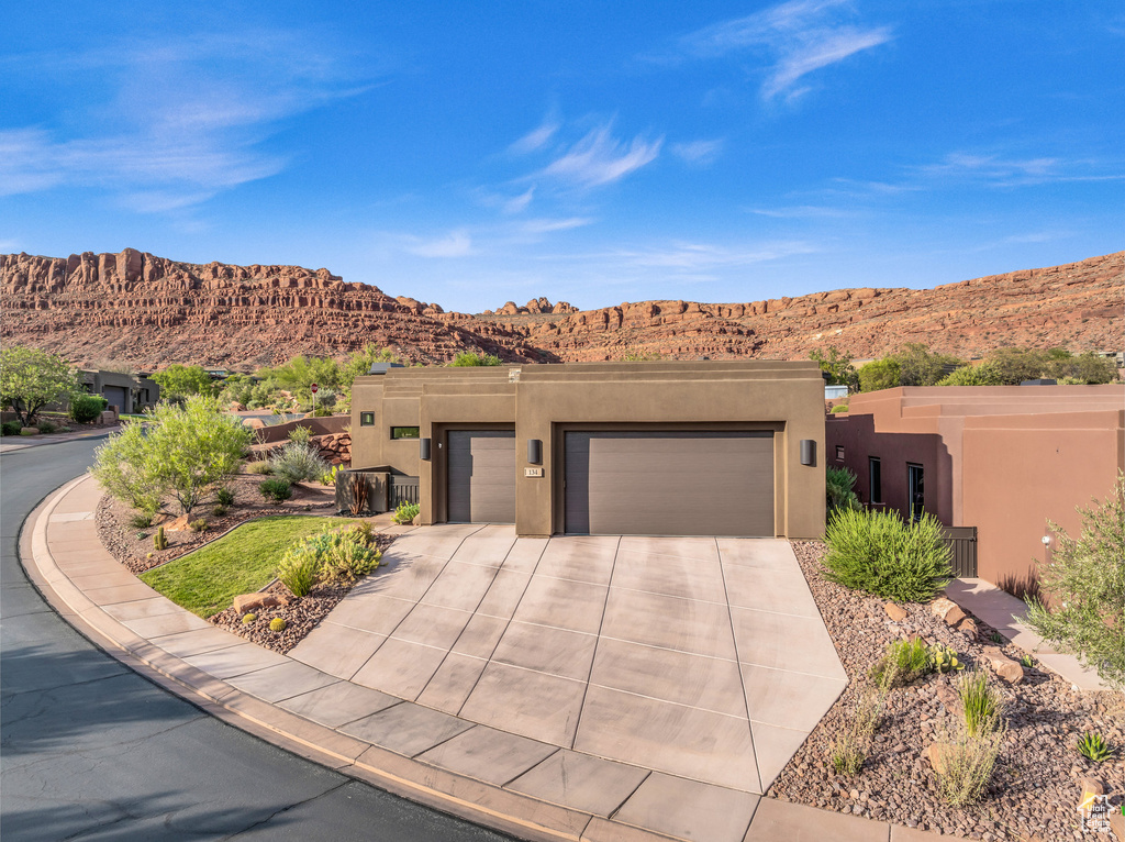 Pueblo-style house featuring a garage and a mountain view