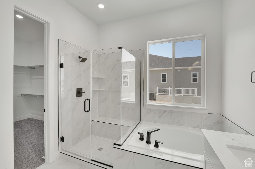 Bathroom featuring a marble finish shower, a bath, a walk in closet, and recessed lighting