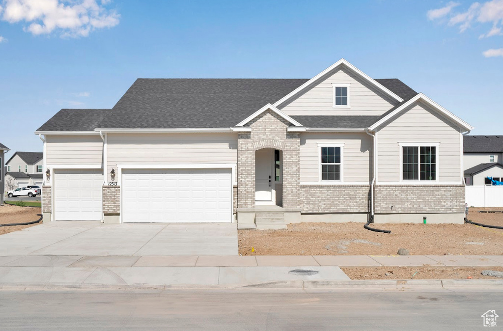 View of front of property featuring a garage, brick siding, concrete driveway, and a shingled roof