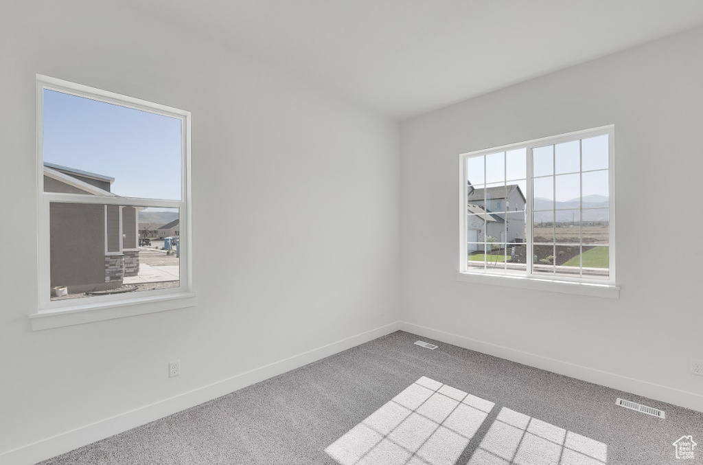 Carpeted spare room featuring baseboards