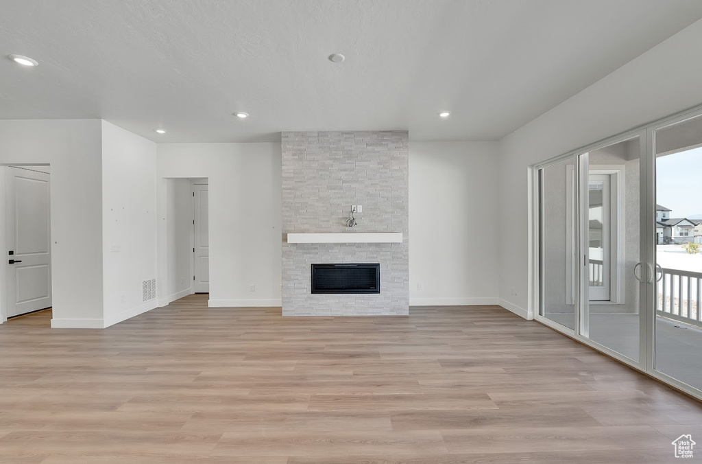 Unfurnished living room with light wood-style flooring, healthy amount of natural light, recessed lighting, and a fireplace