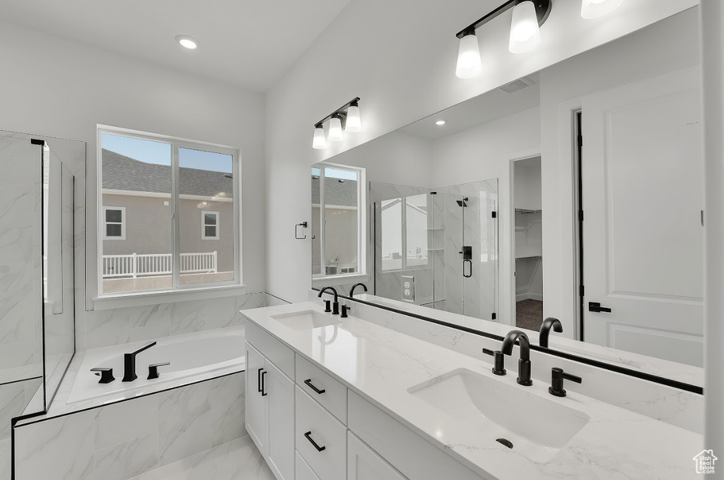 Bathroom featuring a bath, a marble finish shower, double vanity, recessed lighting, and a walk in closet