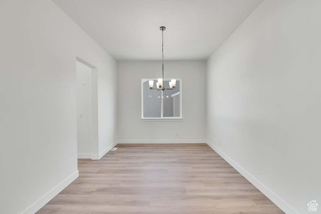 Unfurnished dining area with a chandelier and light wood finished floors