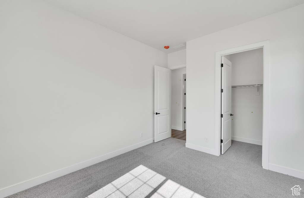 Unfurnished bedroom with carpet, a walk in closet, and a closet