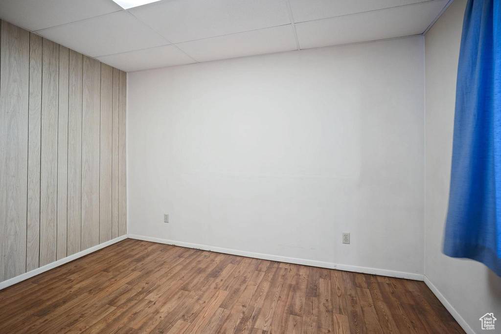 Spare room with hardwood / wood-style flooring, a paneled ceiling, and wood walls