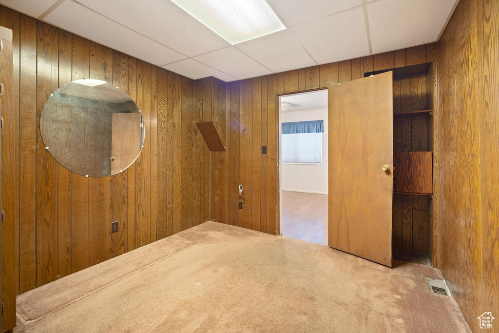 Spare room with a drop ceiling, carpet, and wood walls
