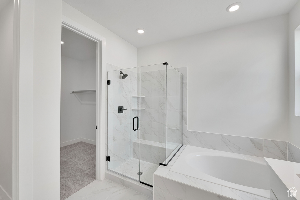 Bathroom featuring a marble finish shower, a bath, recessed lighting, and marble look tiles