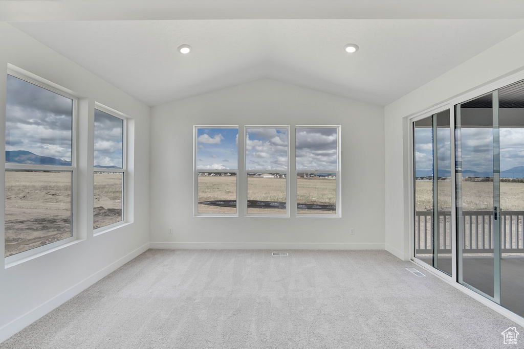 Carpeted empty room with lofted ceiling, healthy amount of natural light, and baseboards