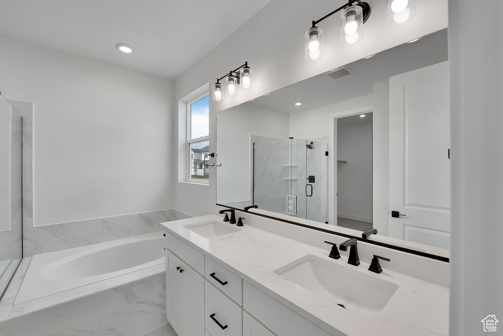 Bathroom featuring a shower stall, a garden tub, double vanity, and recessed lighting