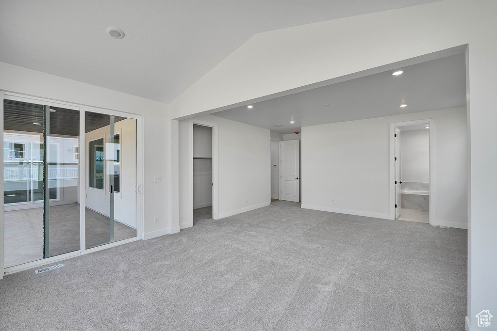 Carpeted empty room featuring vaulted ceiling, recessed lighting, and baseboards