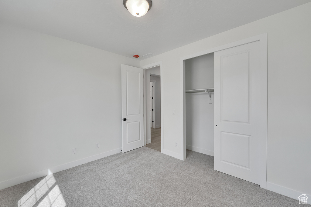 Unfurnished bedroom featuring carpet floors, baseboards, and a closet