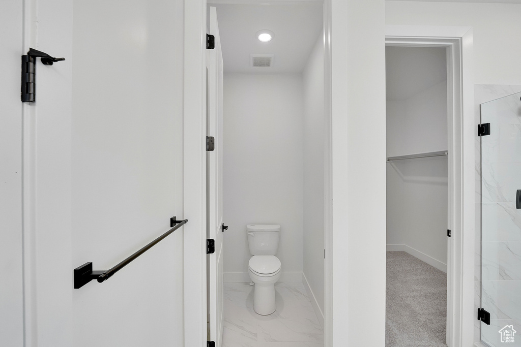 Full bathroom featuring a shower stall, toilet, a spacious closet, and baseboards