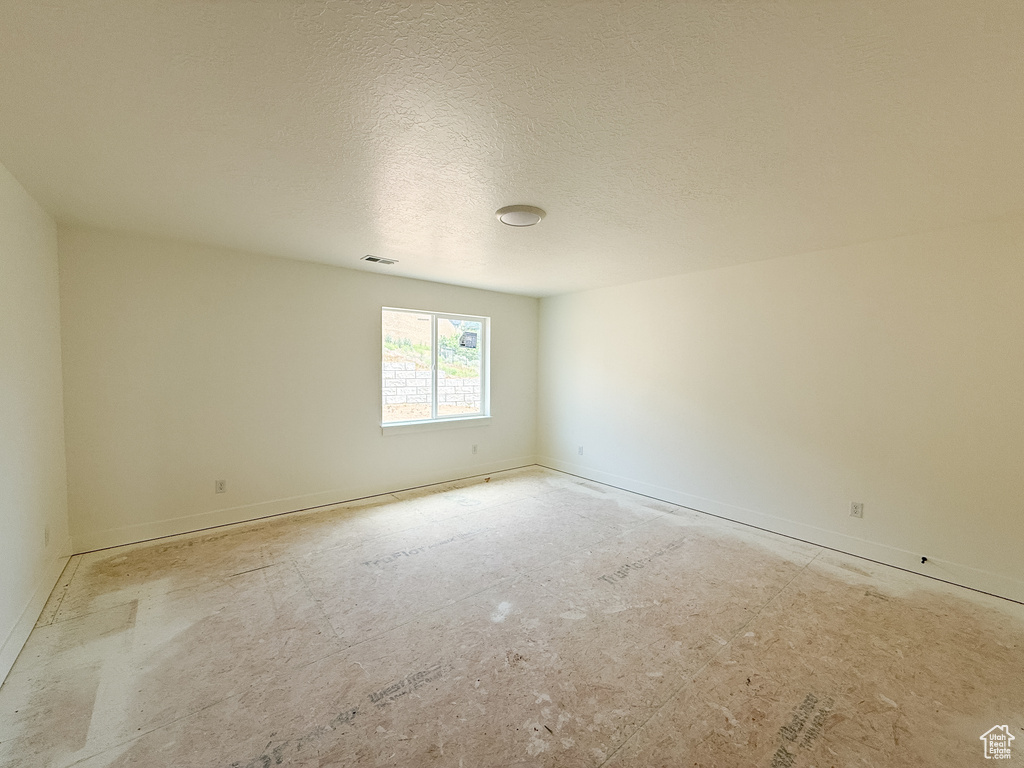 Spare room with baseboards and a textured ceiling