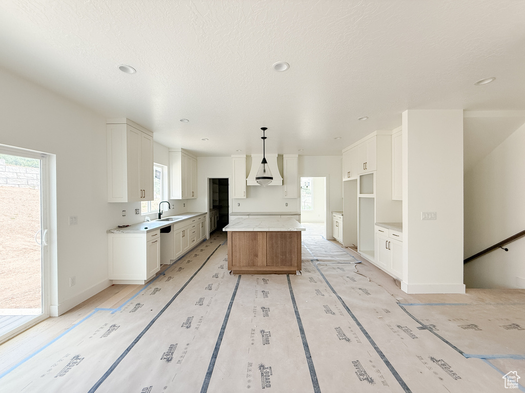 Kitchen with a kitchen island, plenty of natural light, white cabinetry, and recessed lighting