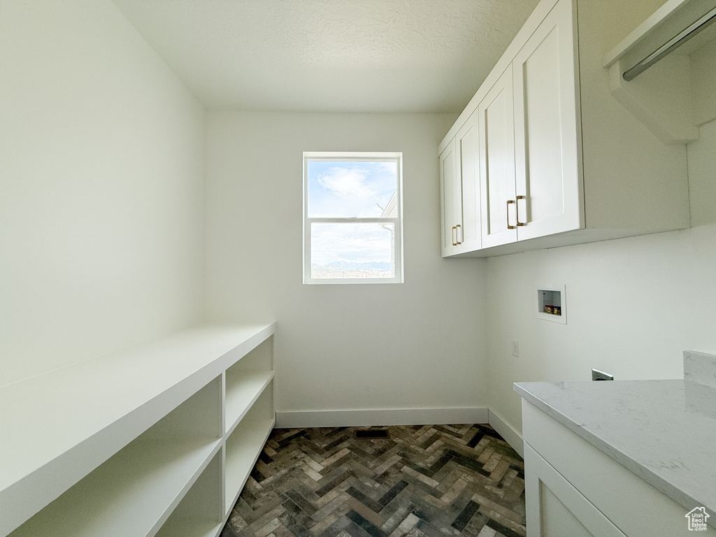 Washroom with cabinet space, washer hookup, and a textured ceiling