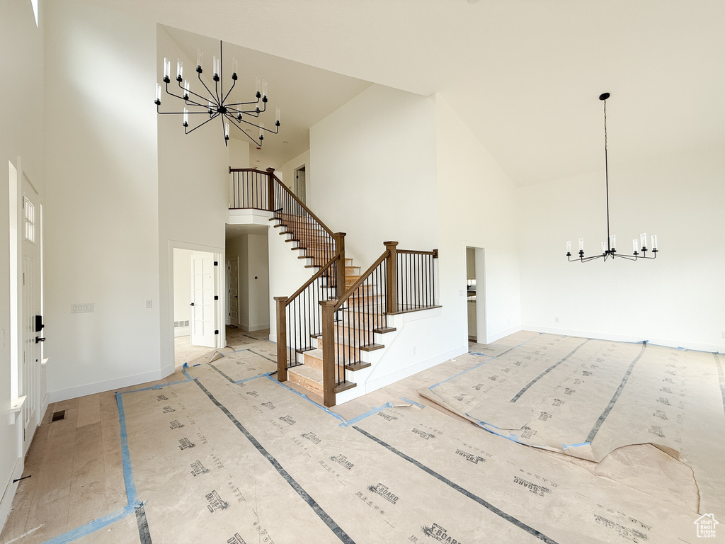 Entrance foyer with high vaulted ceiling, a chandelier, and stairs