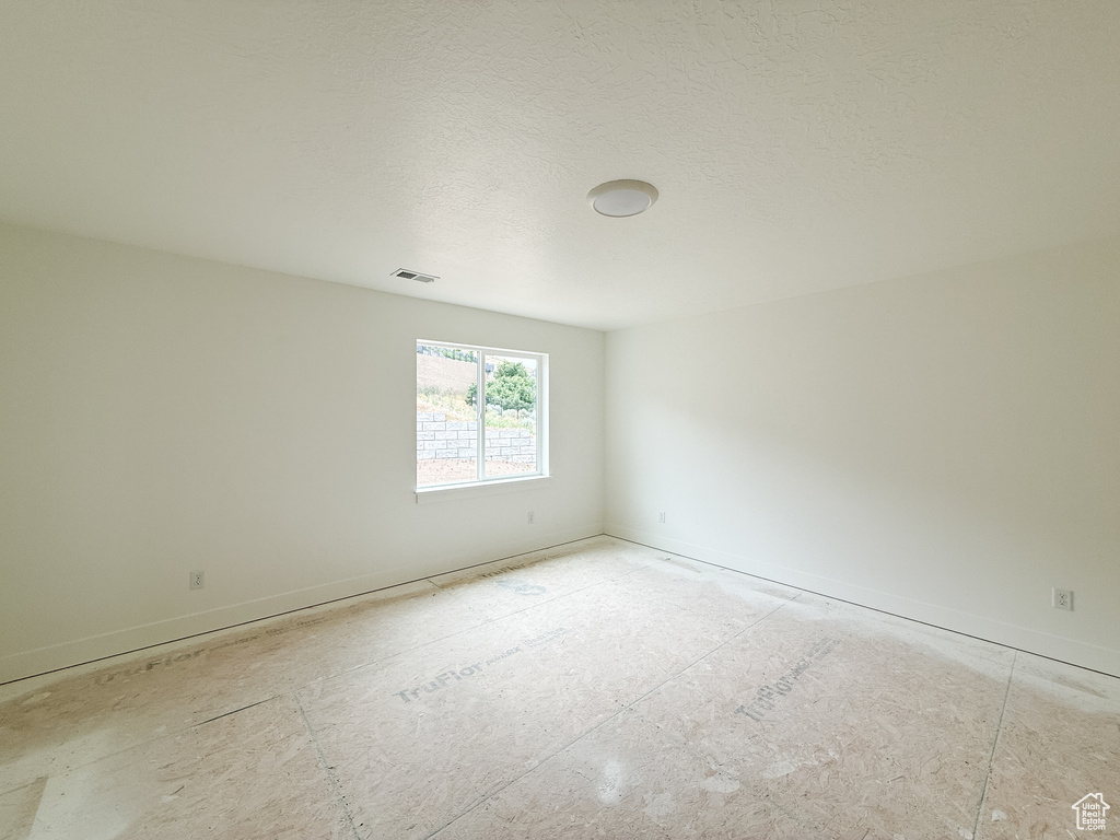 Spare room featuring baseboards and a textured ceiling