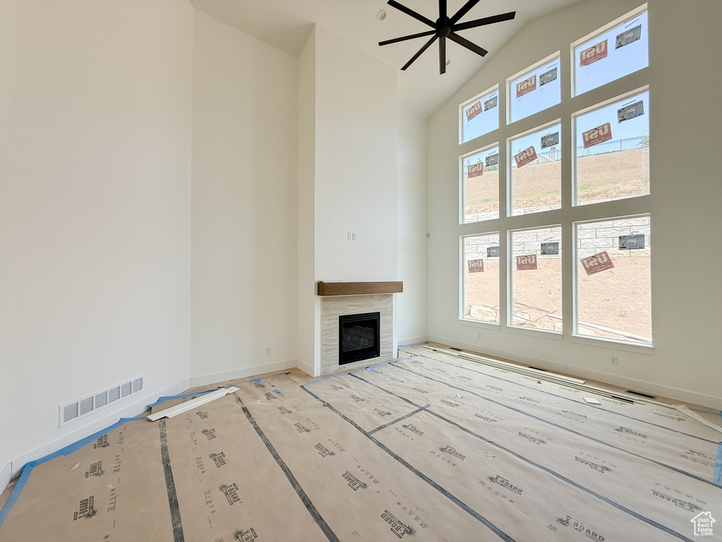 Unfurnished living room featuring high vaulted ceiling, a tile fireplace, and ceiling fan