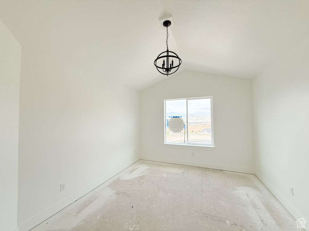 Spare room featuring a chandelier and vaulted ceiling