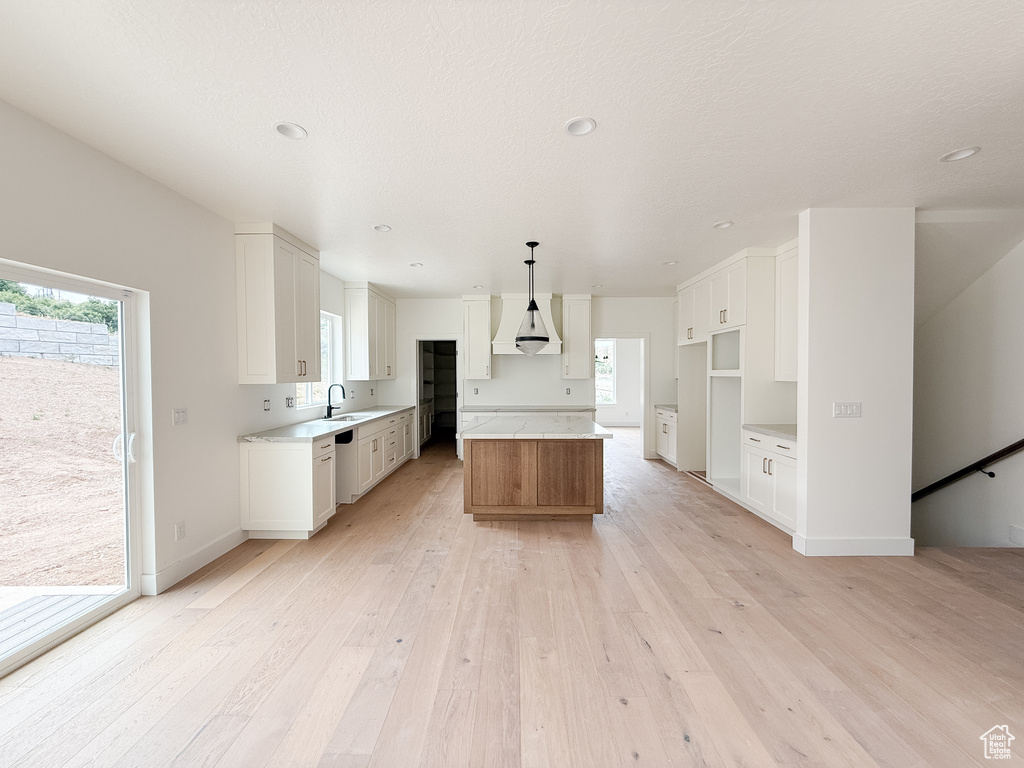 Kitchen with light wood-style flooring, plenty of natural light, a kitchen island, white cabinets, and recessed lighting