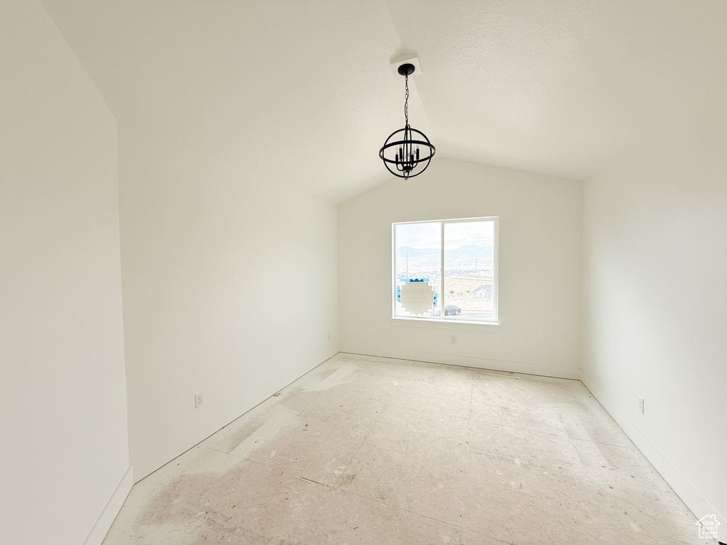 Empty room featuring lofted ceiling and baseboards