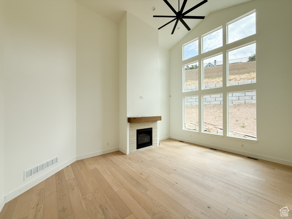 Unfurnished living room featuring high vaulted ceiling, a tile fireplace, and hardwood / wood-style floors