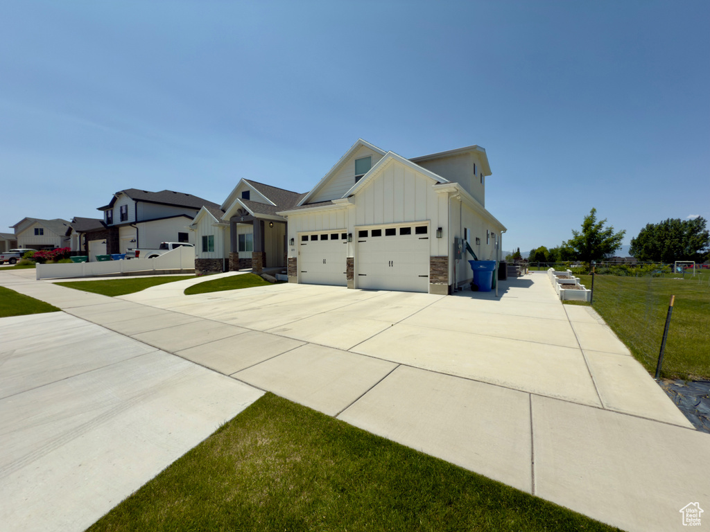 View of side of home with board and batten siding, a garage, driveway, and a yard