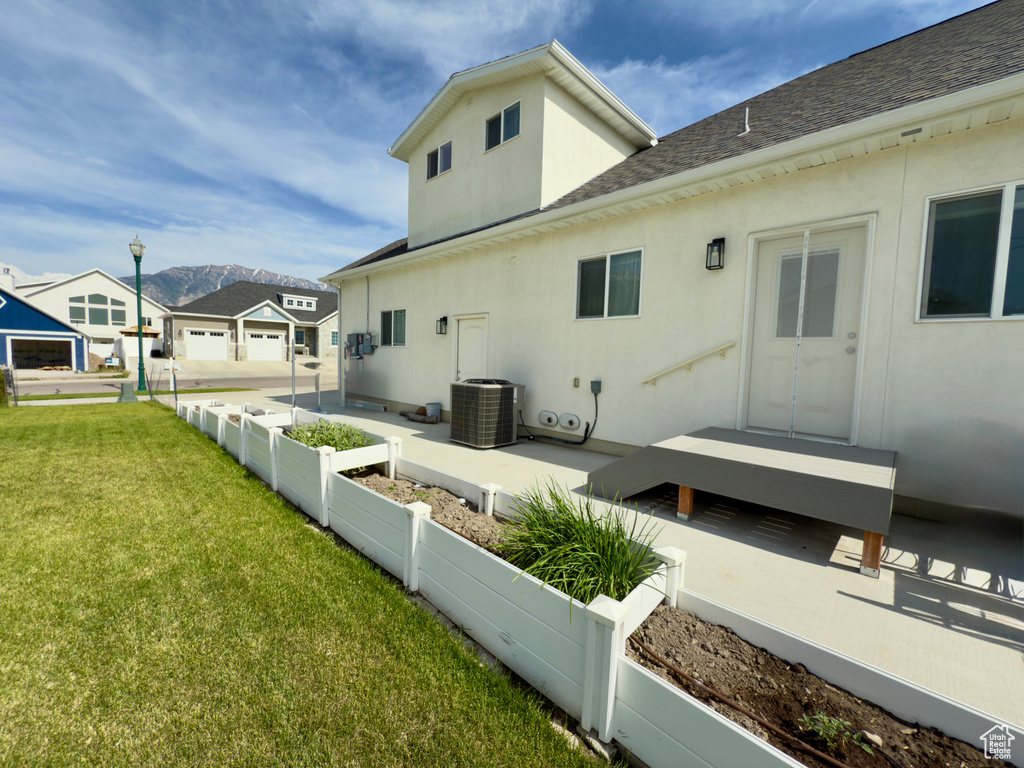 View of side of home with stucco siding, a shingled roof, a mountain view, and cooling unit