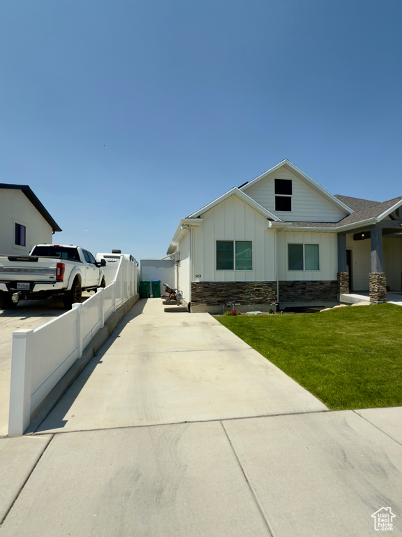 View of front facade featuring board and batten siding, concrete driveway, and stone siding
