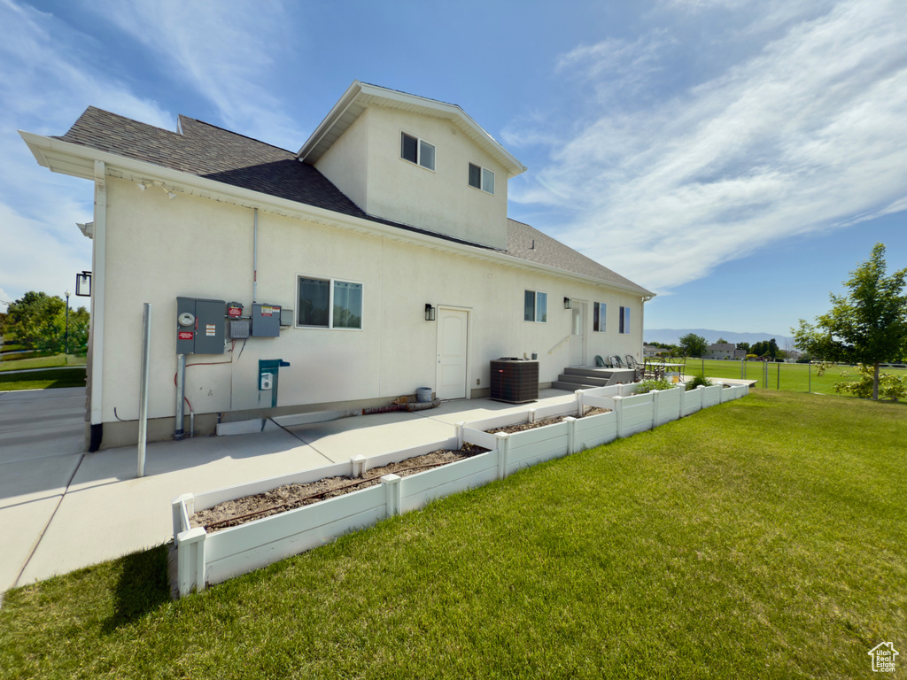 Rear view of house with a shingled roof, stucco siding, cooling unit, an outdoor living space, and a patio