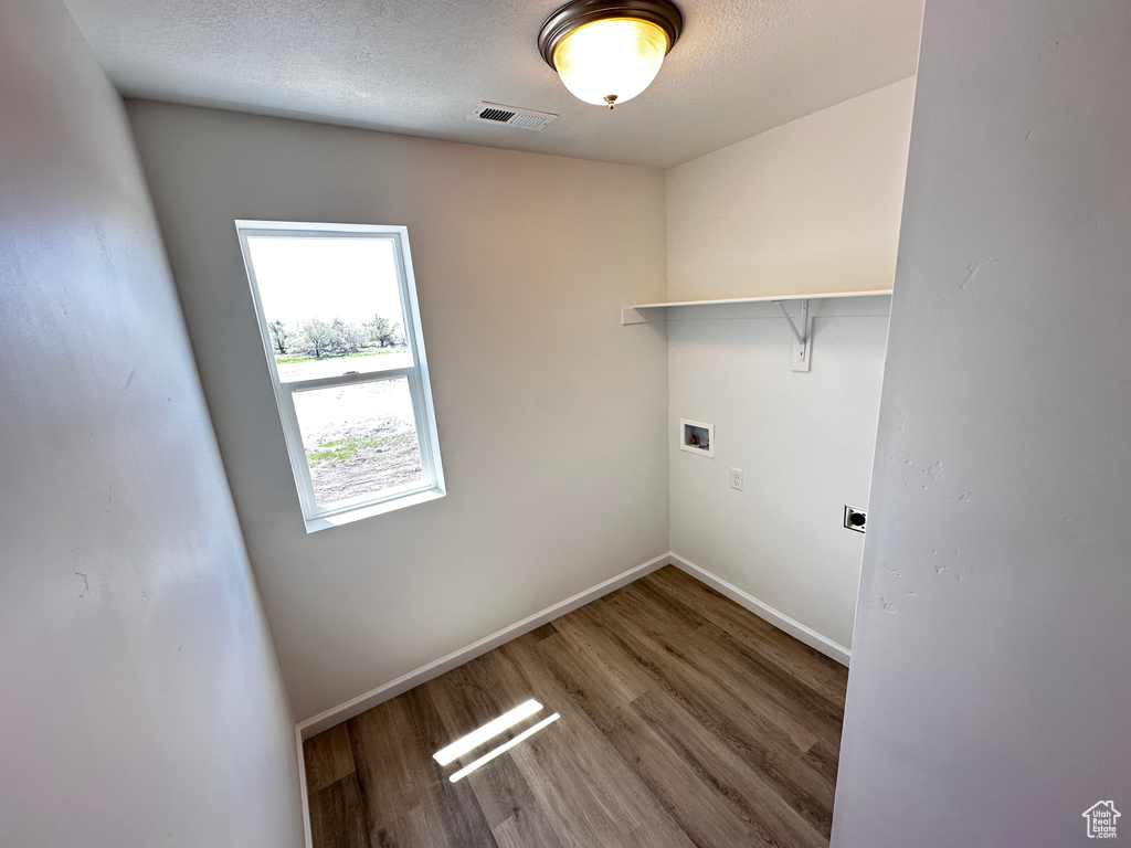 Washroom featuring washer hookup, baseboards, wood finished floors, electric dryer hookup, and a textured ceiling