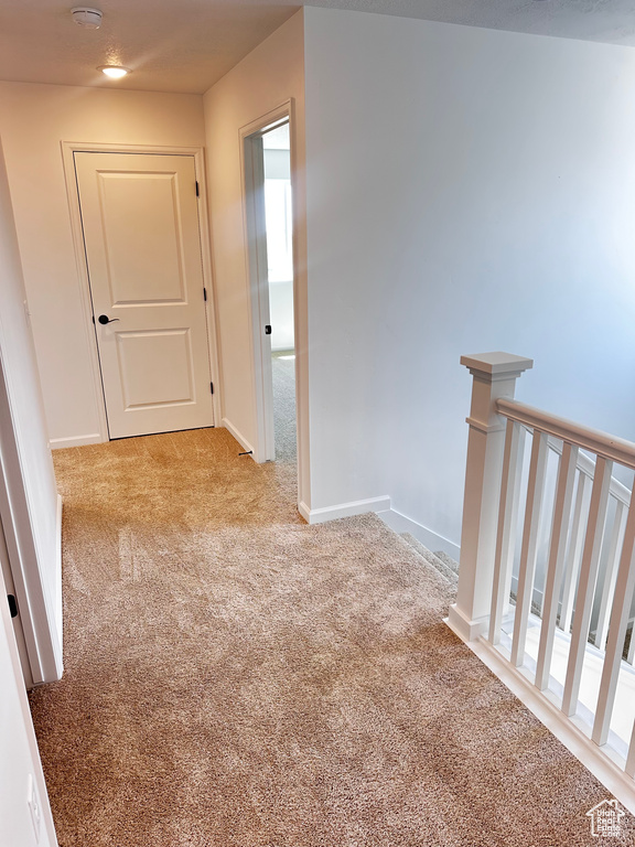 Hallway featuring carpet flooring, an upstairs landing, baseboards, and recessed lighting