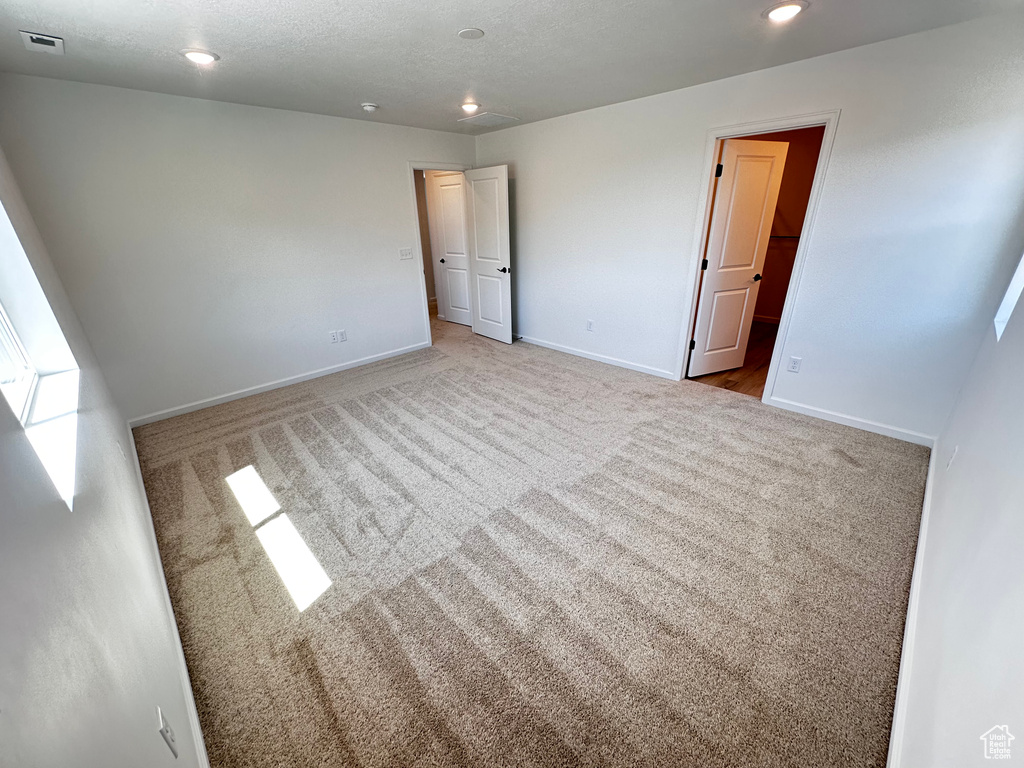Unfurnished bedroom featuring carpet, baseboards, recessed lighting, and a spacious closet