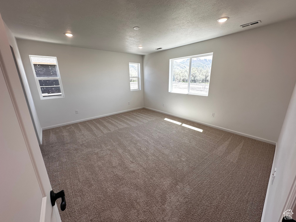 Unfurnished room featuring light carpet, baseboards, a textured ceiling, and recessed lighting