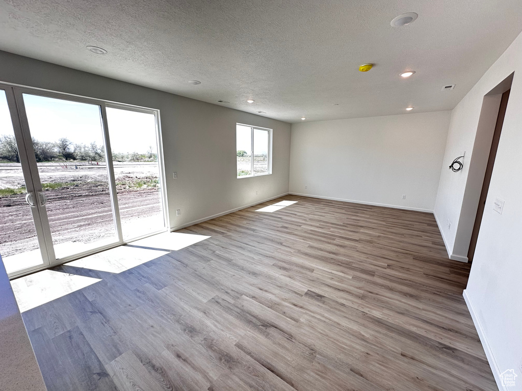 Spare room with baseboards, wood finished floors, recessed lighting, and a textured ceiling