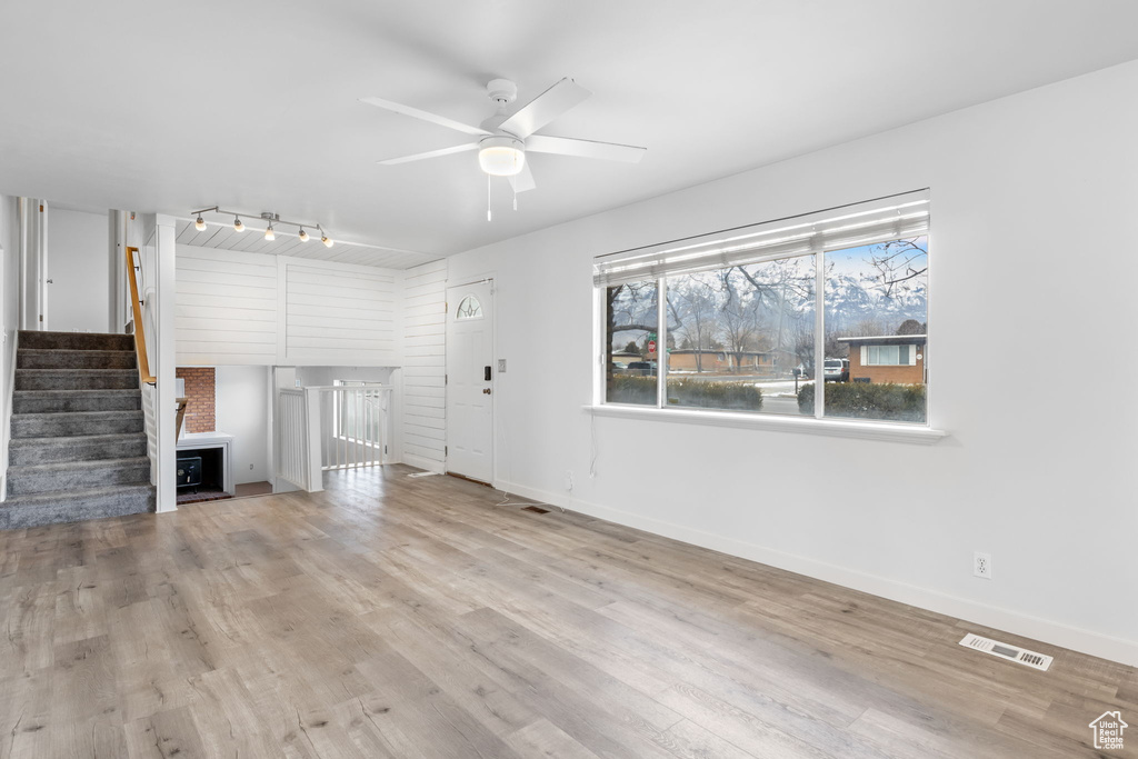 Unfurnished living room with ceiling fan, track lighting, and light wood-type flooring