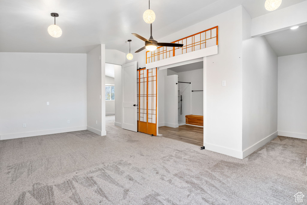 Carpeted empty room with vaulted ceiling and ceiling fan