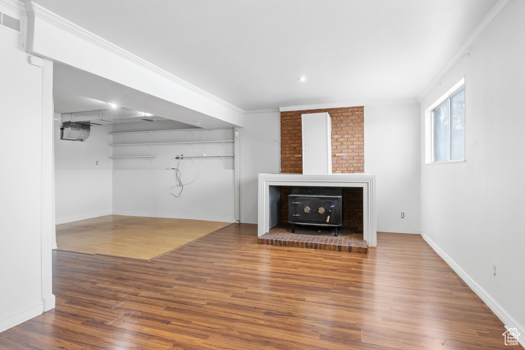 Unfurnished living room featuring crown molding, a wood stove, and dark hardwood / wood-style flooring