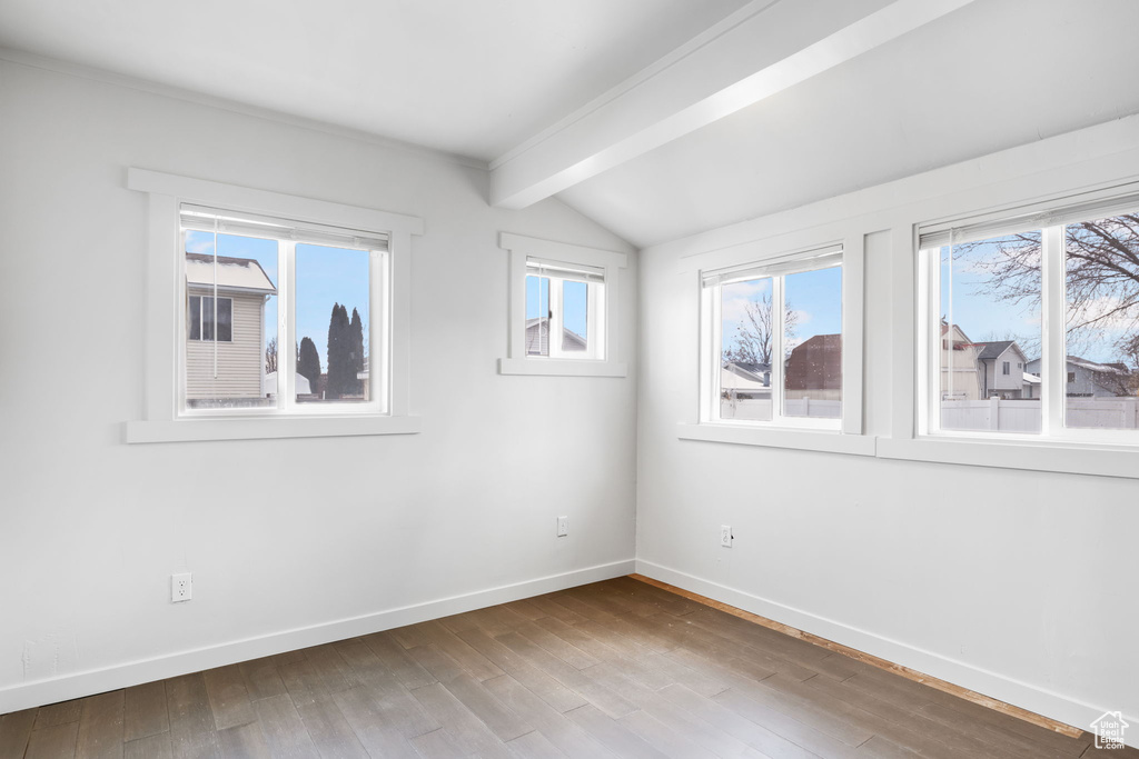 Unfurnished room featuring wood-type flooring and vaulted ceiling with beams