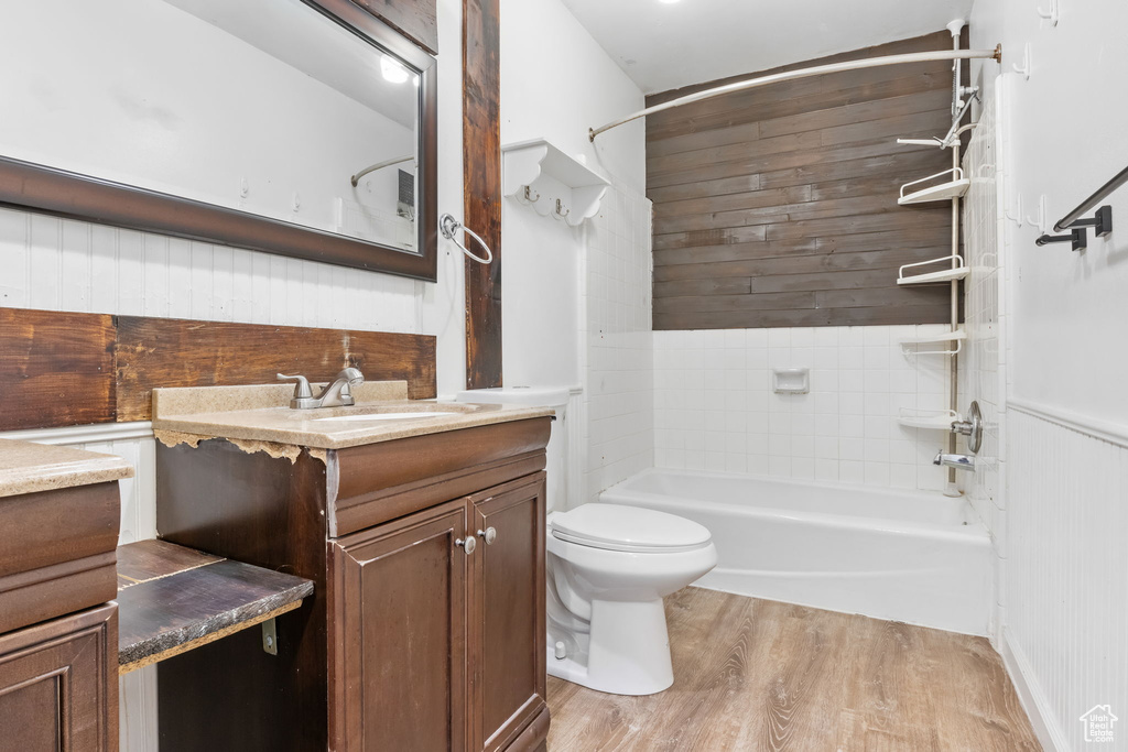 Full bathroom with wood-type flooring, toilet, vanity, and wood walls