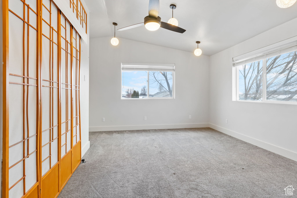 Unfurnished room with lofted ceiling, ceiling fan, and carpet