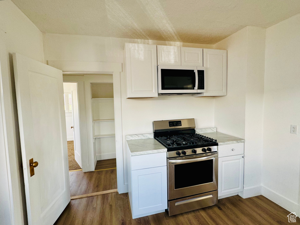 Kitchen featuring white microwave, stainless steel range with gas stovetop, white cabinetry, and light countertops
